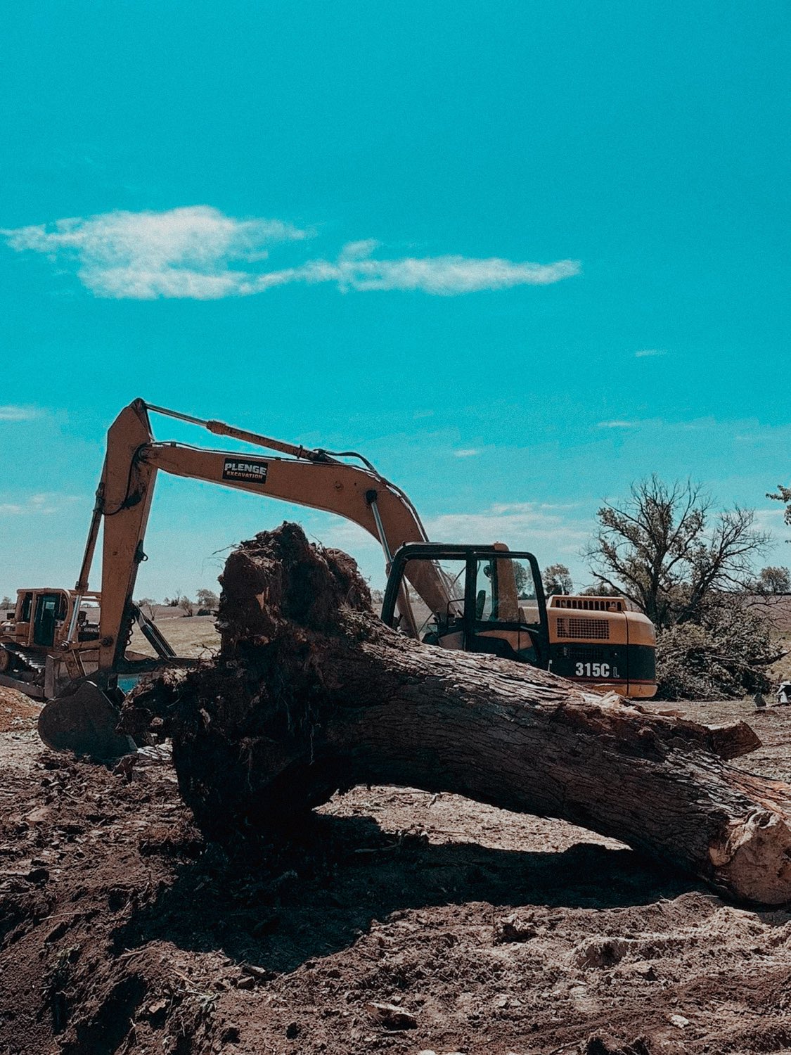 CAT 315C excavator pulling a large tree stump